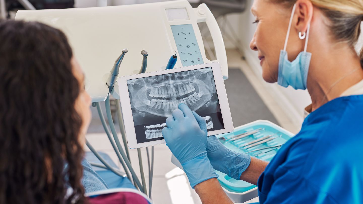 Dentist Showing Dental X-Ray To Patient On Tablet